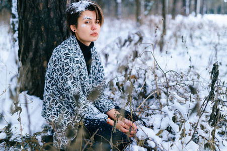 寂寞的女孩坐在冬天的雪林里