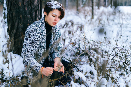 寂寞的女孩坐在冬天的雪林里