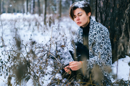 寂寞的女孩坐在冬天的雪林里