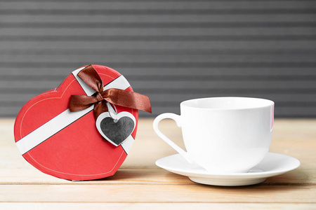关闭礼品盒与咖啡杯在木材背景，情人节概念与咖啡杯和红色盒子