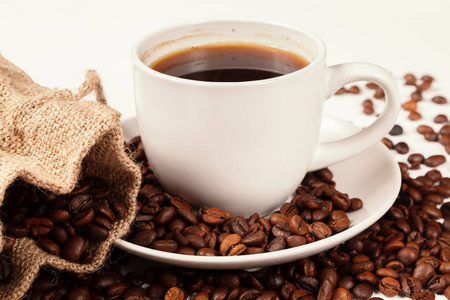 一杯浓咖啡在烤咖啡豆的白色背景隔离。