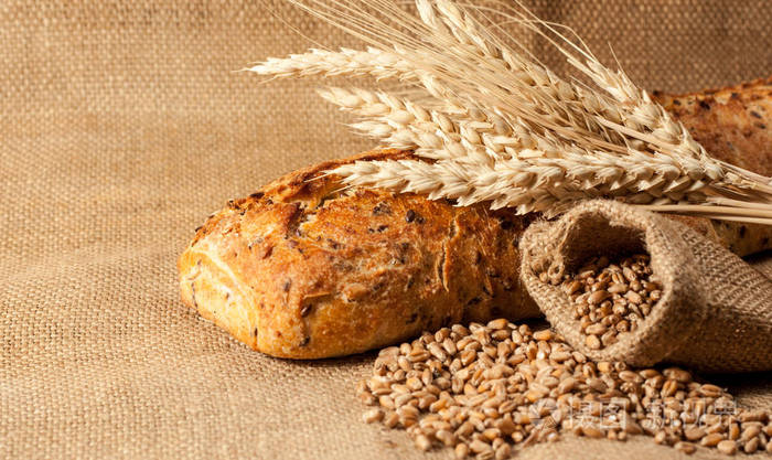 复古面包的乡村风格背景.新鲜的传统面包在木制地面与面粉在一个袋子.