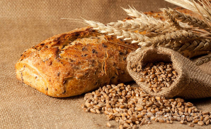 复古面包的乡村风格背景.新鲜的传统面包在木制地面与面粉在一个袋子.