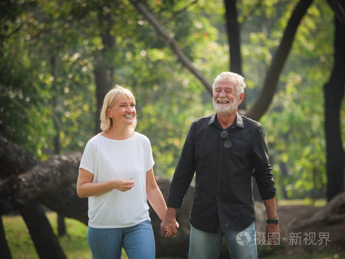 两个快乐的老年人退休,男人和女人在公园里散步和交谈