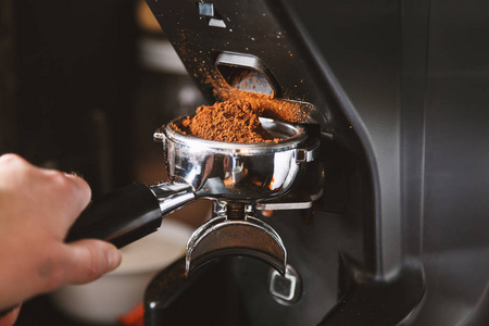 咖啡师用咖啡机磨咖啡豆，用咖啡机磨碎新鲜烘焙的咖啡豆制成粉末。