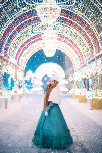 穿着狂欢服装戴着帽子的年轻女孩在冬新年的童话环境中