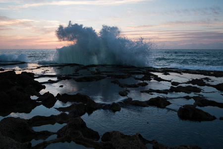 在日落和岩石的背景下, 海浪的飞溅