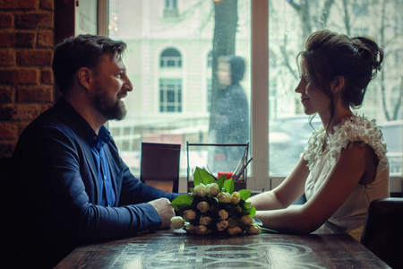 一对恋人坐在窗户附近的咖啡馆里。