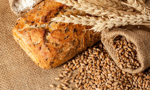 复古面包的乡村风格背景。新鲜的传统面包在木制地面与面粉在一个袋子。