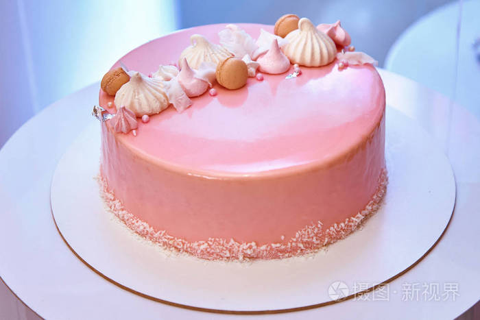 粉红色的蛋糕夹着棉花糖和纸杯蛋糕放在盘子里