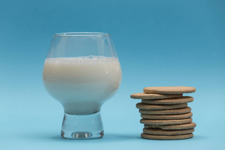 一杯牛奶，形状像杯子，蓝色背景上有一小列饼干