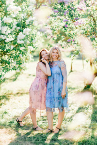 年轻的双胞胎姐妹穿着不同的衣服盛开的夏季植物园