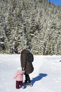 幸福的家庭母亲和孩子女儿有乐趣，拥抱在一个冬天的雪山。育儿概念