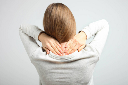 生病的女人,颈部疼痛在中立的背景后视图. 概念疾病.照片
