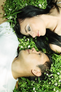年轻夫妇面对面躺在草地上