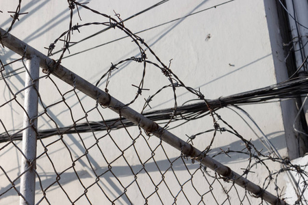 带有铁丝网的栅栏，背景通常围绕监狱国家边界和私人财产。 社会非法移民难民社会问题的灰色背景。 选择性聚焦