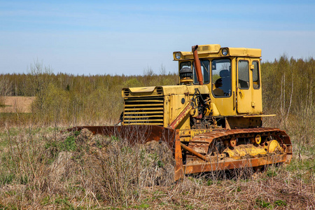 老黄锈履带拖拉机在田里。 老履带拖拉机在杂草丛生的田间拉脱维亚。