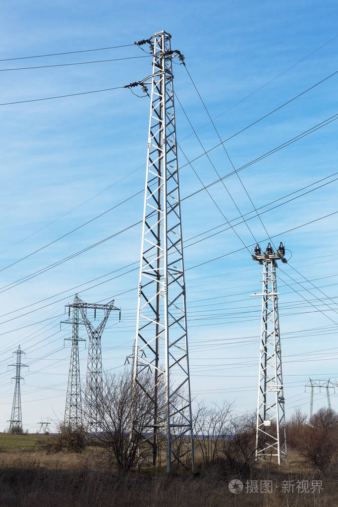 高压线路和电力塔在一个平坦和绿色的农业景观在一个阳光明媚的日子