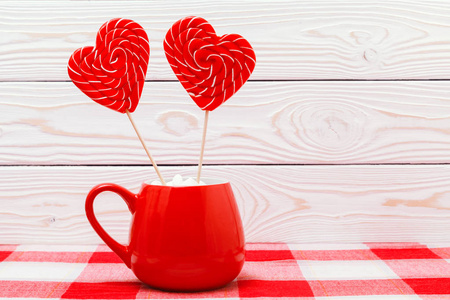 s day background. Two heart shaped lollipops in a red Cup, on a 