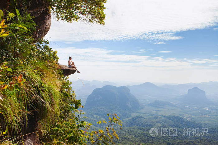 年轻女子坐在悬崖上放松. 旅行概念