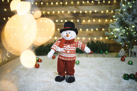 穿着毛衣的雪人站在圣诞灯光下