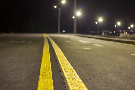 宽阔的现代光滑的空灯，路灯，沥青公路，夜间有明亮的白色标志线。 速度安全舒适的旅程和专业的道路建设理念。