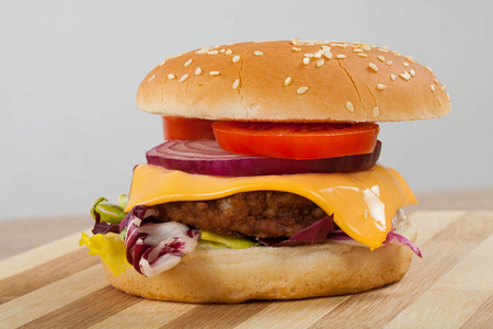特写一个美味的芝士汉堡，里面有牛肉切达干酪芝麻生菜