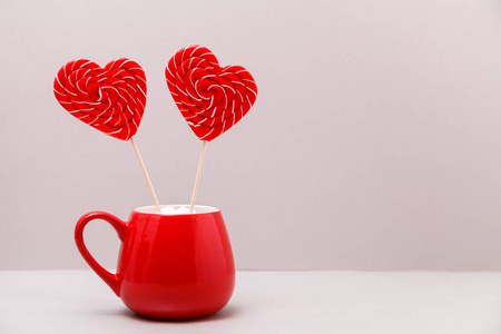 s day background. Two heartshaped lollipops in a red Cup, on a 