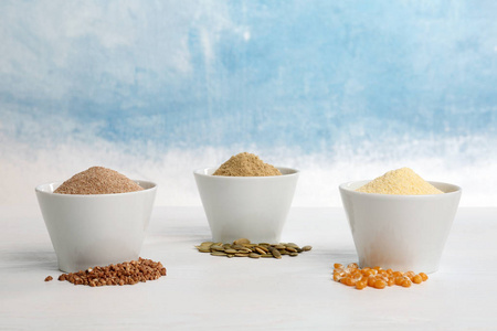 碗与不同类型的面粉和种子在桌子上的颜色背景。 文本空间