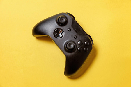 黑色操纵杆游戏板，游戏机上的黄色彩色时尚别针背景。电脑游戏竞赛电玩控制对抗概念。网络空间符号
