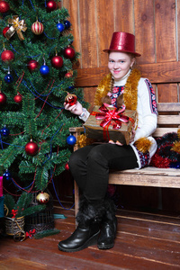 带礼物的微笑女孩坐在圣诞树旁