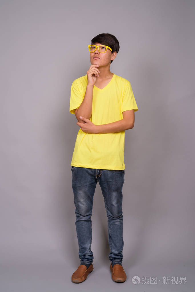 灰色背景的年轻的亚洲十几岁的男孩