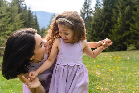 在草地上穿着紫色裙子的母亲和女儿