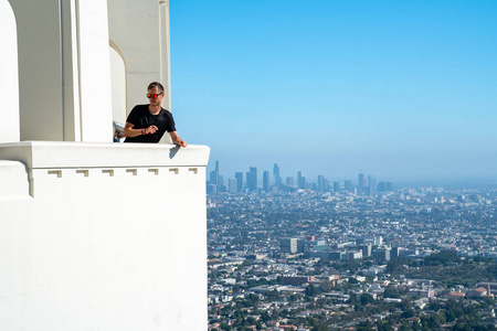 年轻人坐在洛杉矶市中心的背景下。 令人惊叹的好莱坞。