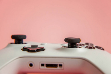 白色操纵杆Gamepad游戏控制台在粉红色色彩鲜艳的现代时尚别针背景。 电脑游戏竞争视频游戏控制对抗的概念。 网络符号