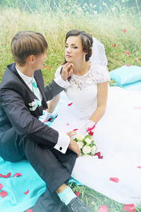 新娘和新郎坐在玫瑰花瓣的绿草上