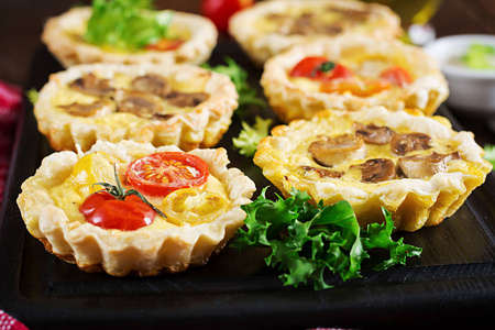 蘑菇，切达干酪，木制背景上的西红柿馅饼。小馅饼。美味的开胃菜，小吃。