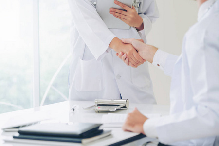医院的医生向另一位医生握手，展示了专业医护人员的成功和团队合作。