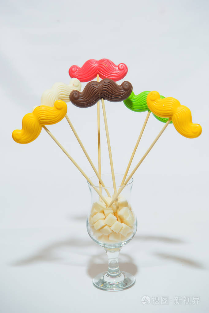 五颜六色的胡子形状的糖果. 在釉上画微笑. 杯子里的糖果.