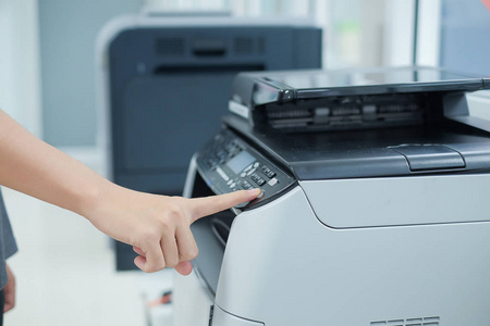 办公室打印机扫描仪或激光复印机面板上的女士手按按钮