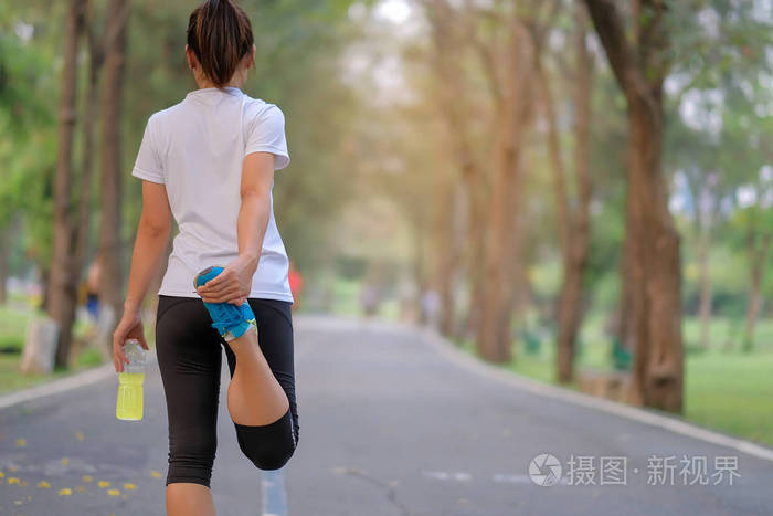 年轻的运动员女士在公园里闲逛,户外女跑步者热身,准备在亚洲健身以外