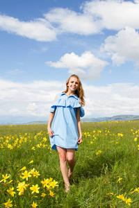 穿着一件短蓝色连衣裙的女孩在花丛中散步