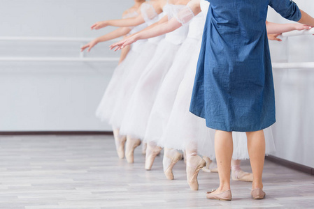 脚在尖角。 芭蕾舞学校的练习。 芭蕾课。 一群站在一排的女孩伸出他们的腿在尖上粗制滥造。 穿白色裙子的孩子。 老师上舞蹈课。