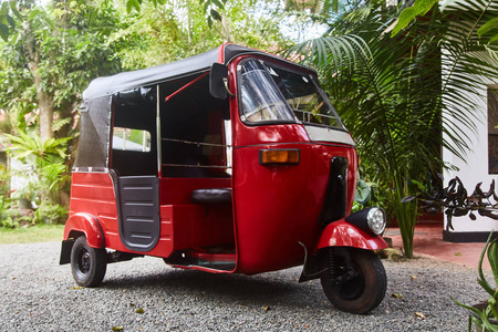 斯里兰卡男子斯里兰卡公路上的红色三轮车出租车.锡兰旅游车照片