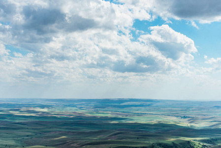 小山地平线蓝天上有蓬松的云彩. 白色卷云被太阳照亮.