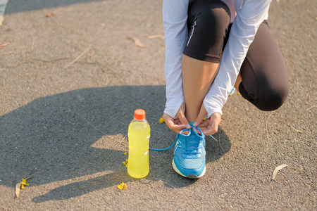 年轻的运动员女士在公园户外系跑鞋，女跑步者准备在外面的路上慢跑，亚洲健身步行和早上在人行道上锻炼。健康和体育概念