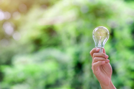 手持灯泡，绿色背景。新理念创意天才创新和太阳能概念