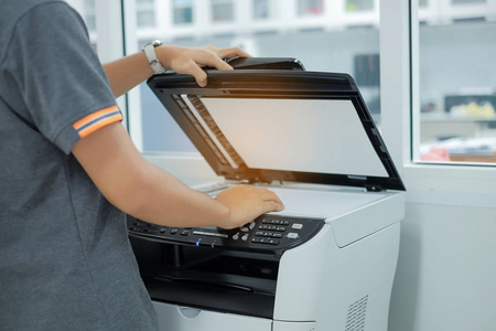 商务女性在办公室用手将文件纸放入打印机扫描仪或激光复印机
