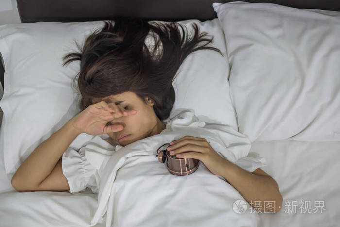 亚洲女人睡在床上带复古闹钟年轻女性晚上躺在卧室内部快乐睡眠概念