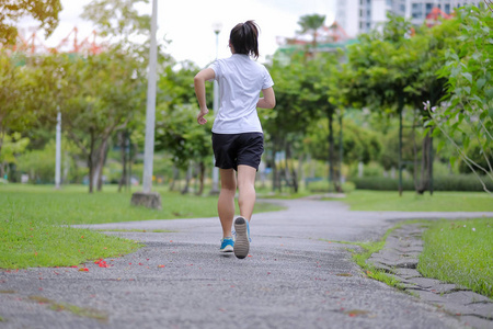 年轻的健身妇女在公园户外散步，女跑步者在外面的路上跑步，亚洲运动员在阳光明媚的早晨慢跑和在小径上锻炼。体育健康和健康概念